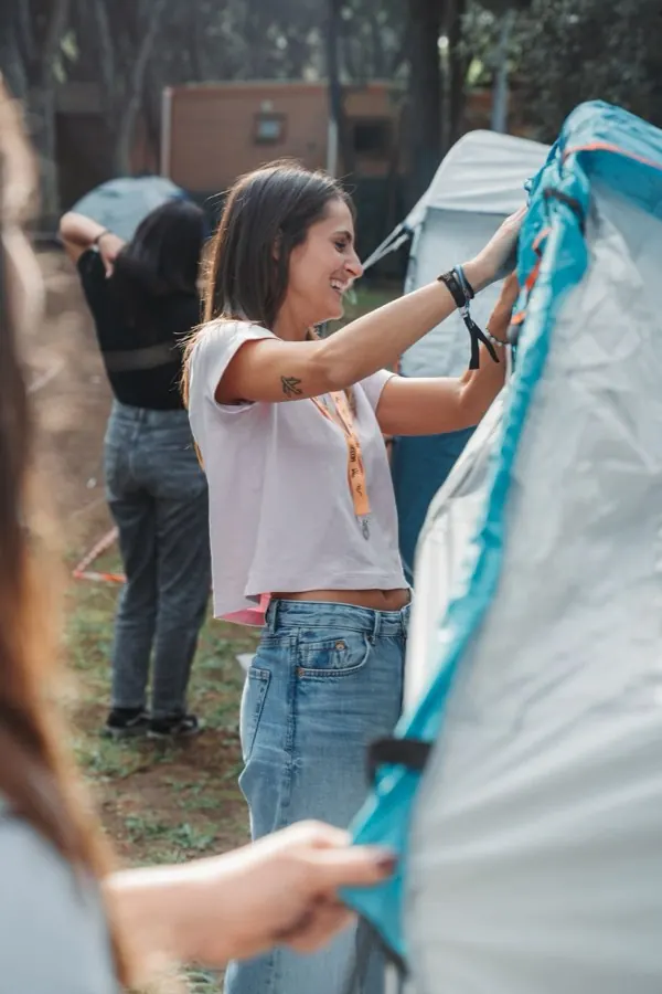 Persone che montano una tenda tra gli alberi